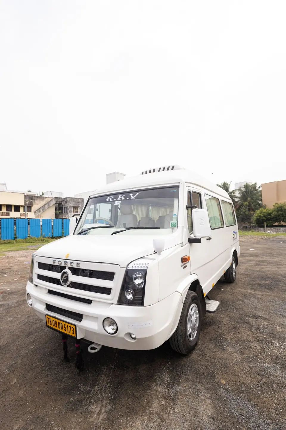 White high-roof tempo traveller parked in an open yard in Chennai