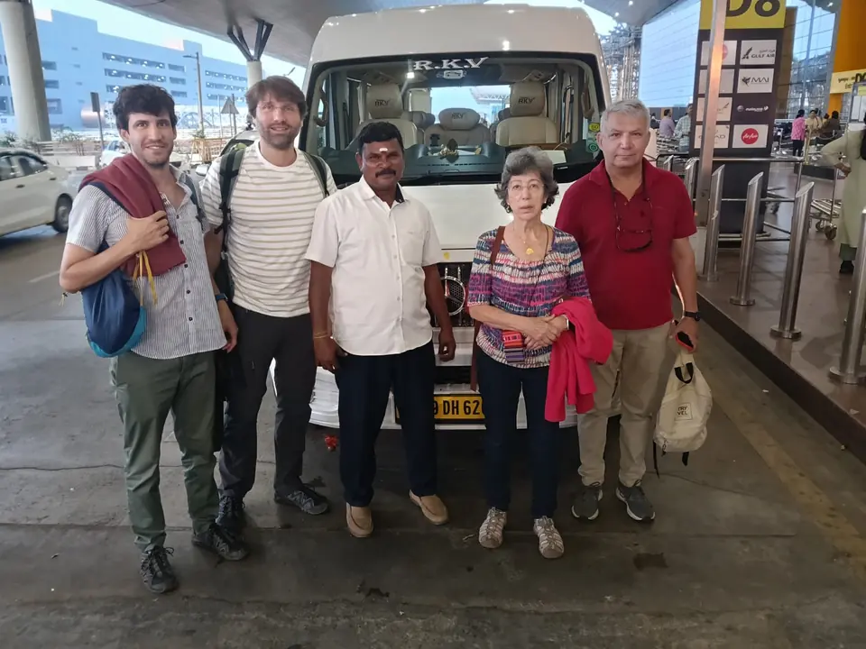 Overseas guests with backpacks and our driver beside a tempo traveller at the airport departures lane
