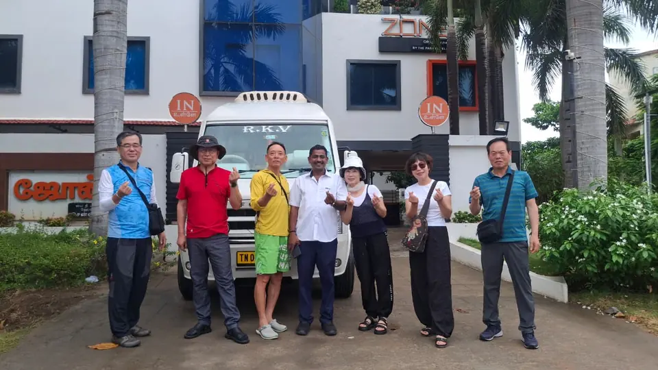 East Asian business travellers with our driver in front of an RKV tempo traveller at a hotel