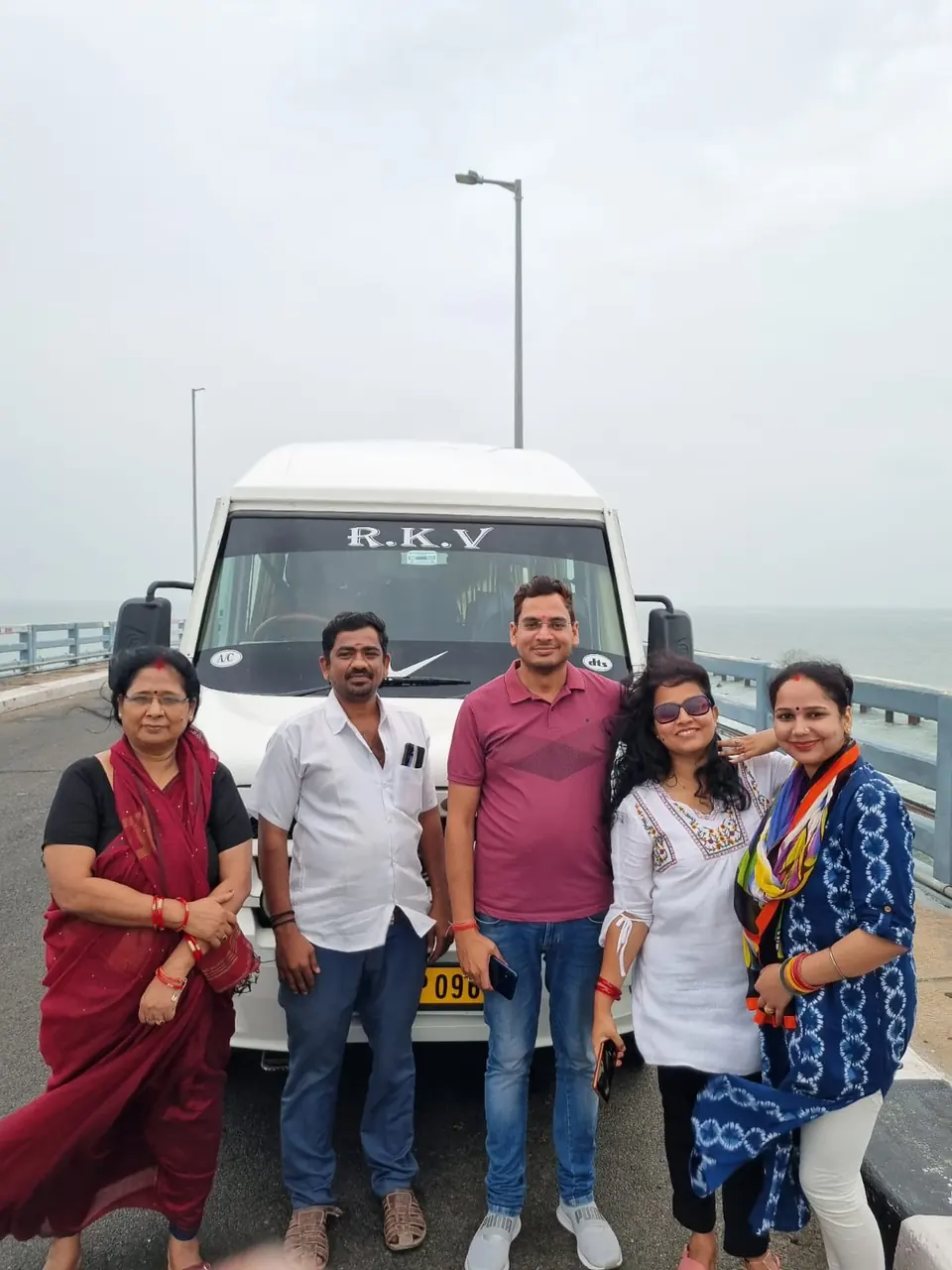 Family of five in front of an RKV tempo traveller on a bridge by the water
