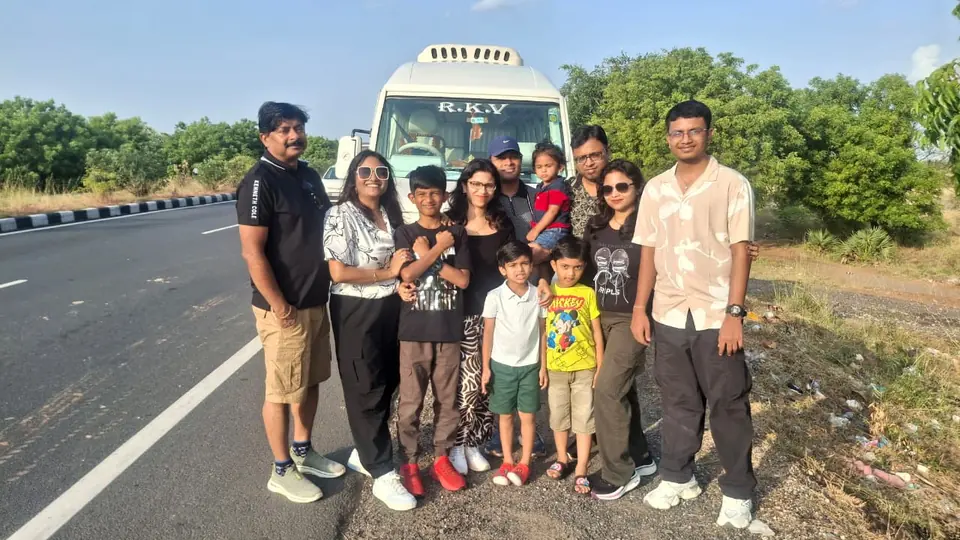 Family with children standing on a highway shoulder in front of a tempo traveller