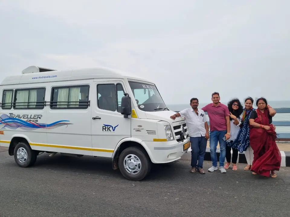 Family standing beside a long-body tempo traveller on a coastal road