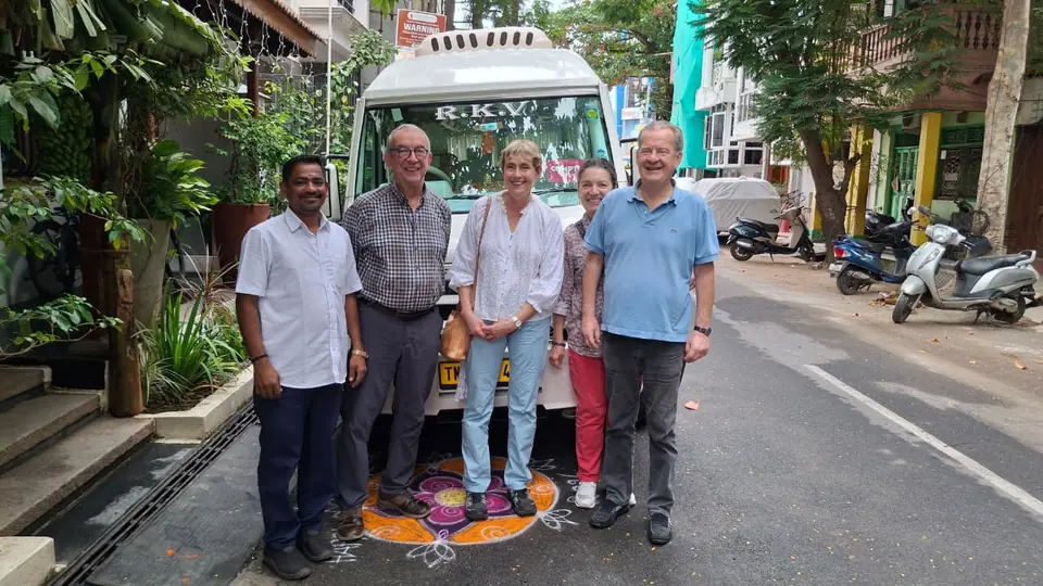 Guests with our driver on a Chennai street beside a kolam, in front of the tempo traveller