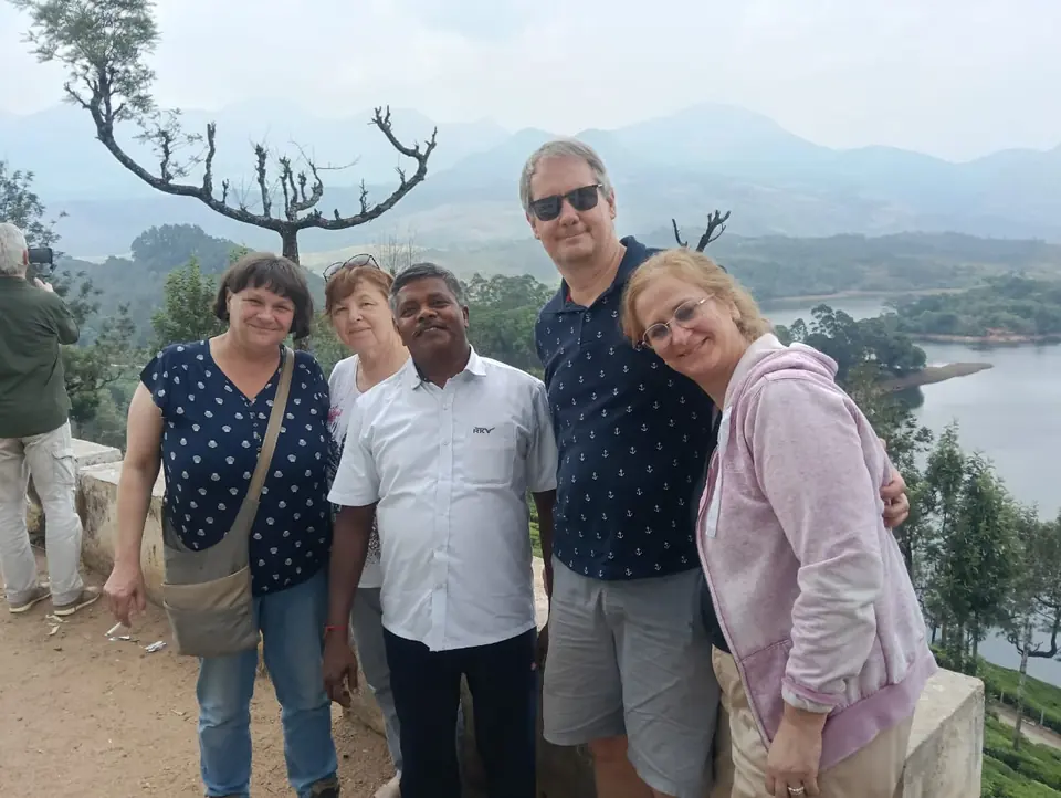 Overseas guests with their RKV driver at a hill viewpoint overlooking a lake and mountains