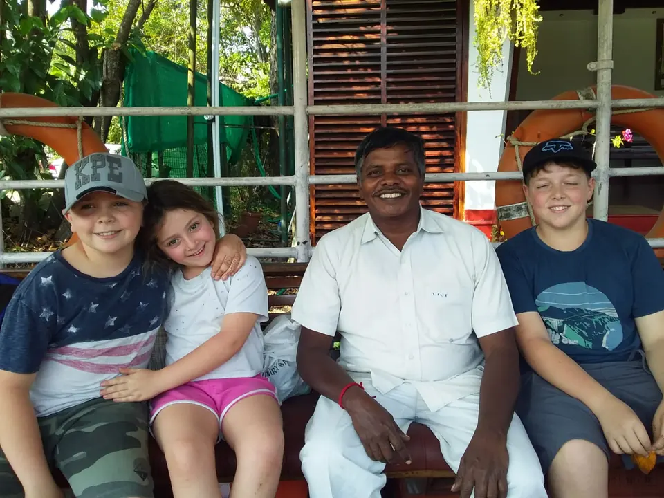 Two children and a young traveller sitting with our smiling driver