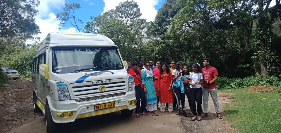 Family group beside a tempo traveller in a green forest clearing