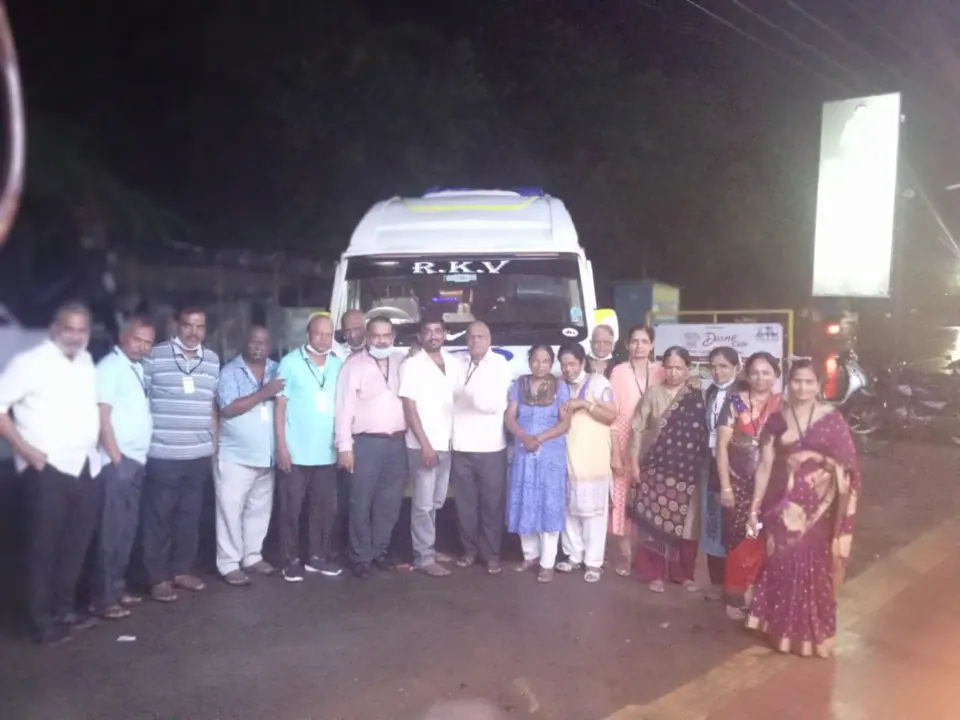 Large group of about twenty people at night in front of an RKV tempo traveller