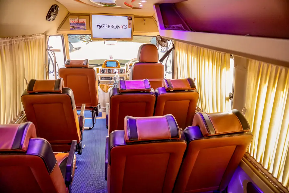 Luxury tempo traveller interior with tan leather pushback seats, LED lights and a front TV screen