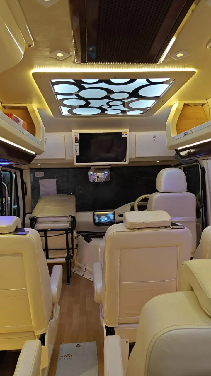 Maharaja tempo traveller interior with a designer LED ceiling panel, TV and cream recliners