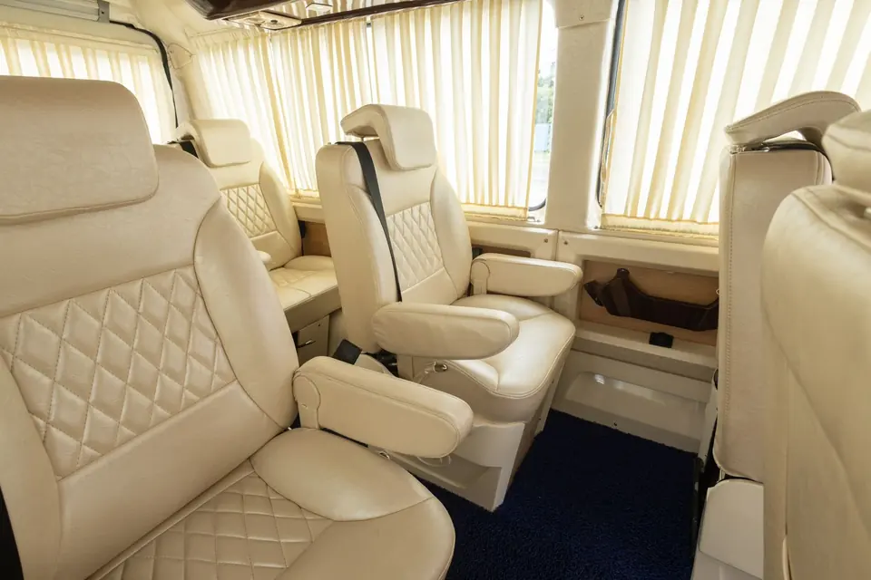Cream quilted leather captain seats with armrests inside a Maharaja tempo traveller