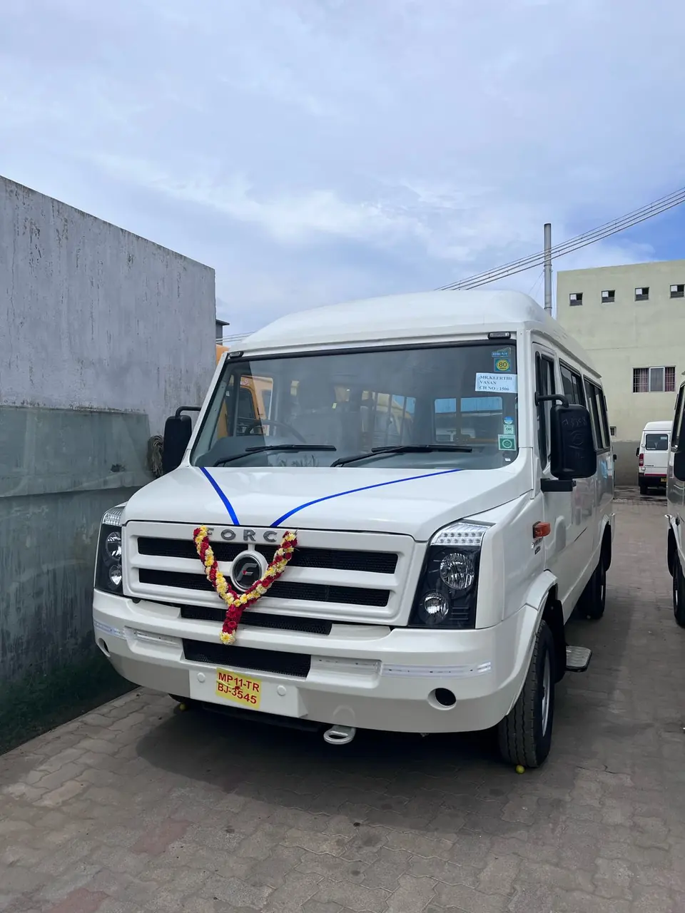 Brand-new tempo traveller with a flower garland on the grille after its vehicle pooja