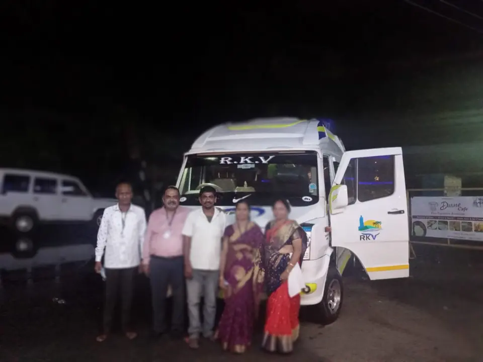 Family group at night beside an RKV tempo traveller with its door open