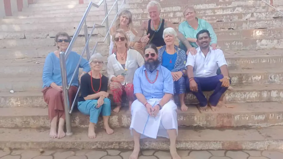 Tour group seated on stone temple steps with their RKV driver