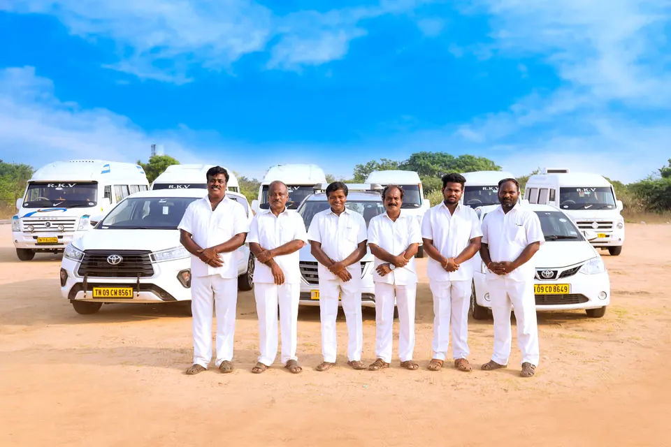 Six RKV drivers in white uniforms standing in front of the fleet of tempo travellers and cars