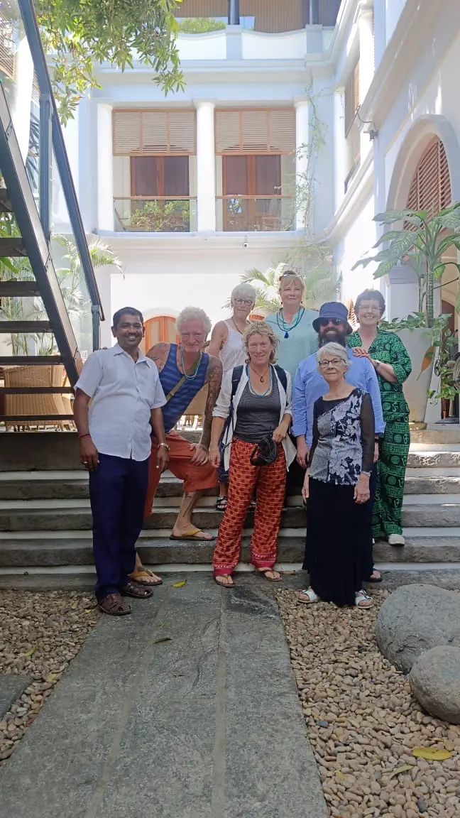 Senior travellers with their driver in front of a white heritage house
