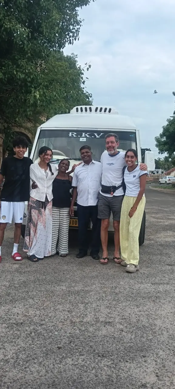 Small group of travellers with their driver in front of an RKV tempo traveller