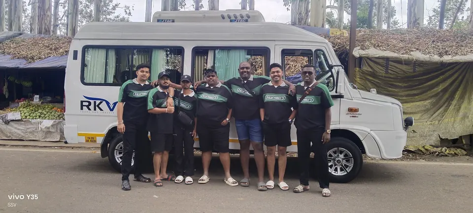 Sports team in matching jerseys standing beside an RKV tempo traveller