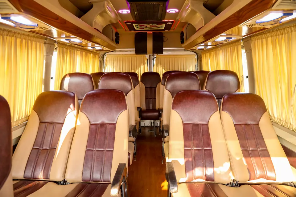 Two-by-one reclining seats in maroon and cream leather inside a tempo traveller with wooden flooring