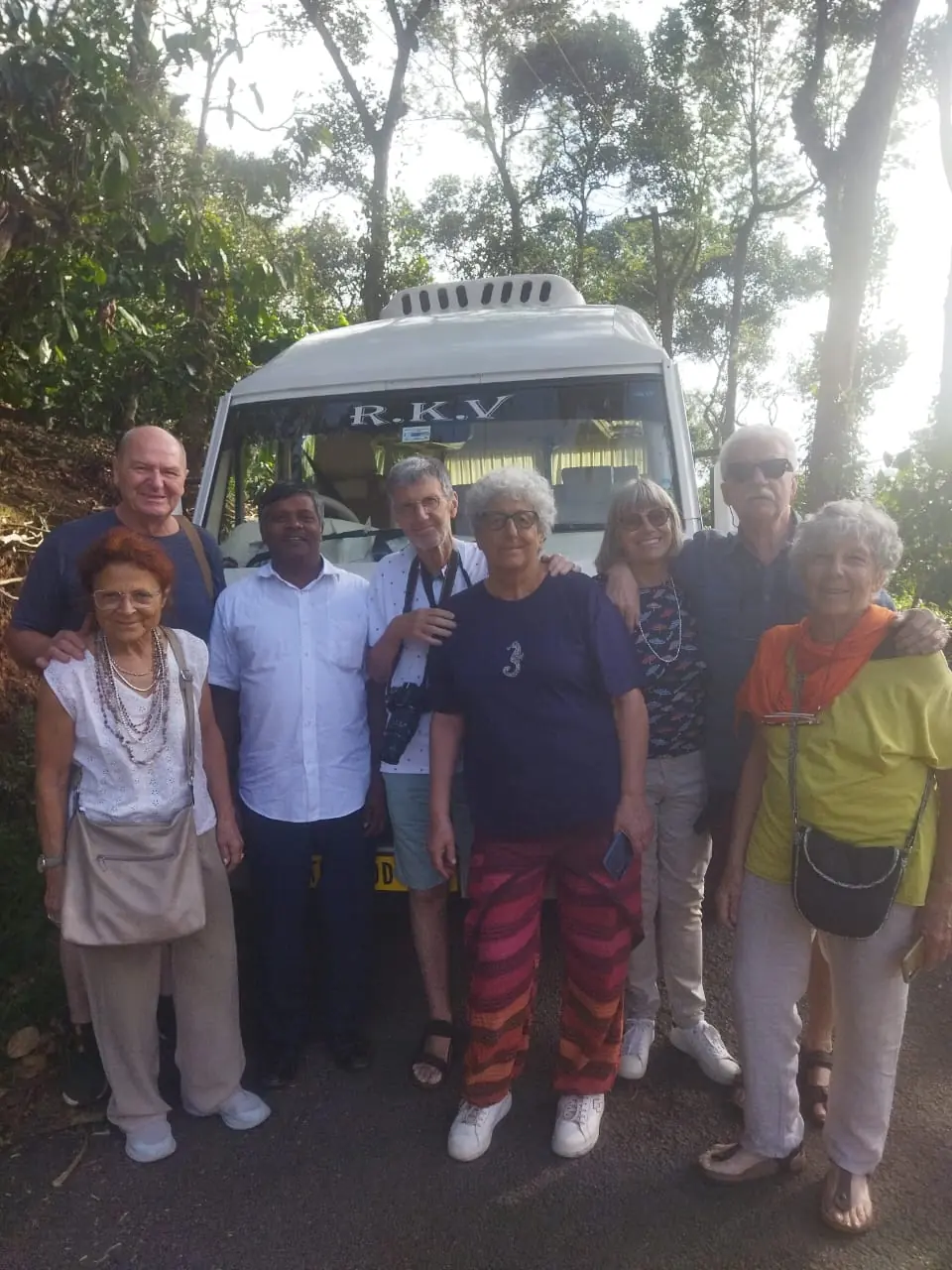 Group of overseas travellers with their RKV driver in front of a tempo traveller